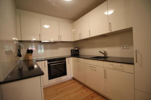 a kitchen with white cabinets and black counter tops at Ferienwohnungen Felsenkeller Bielatal in Bielatal