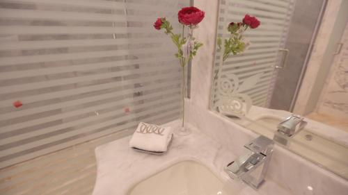 a bathroom with two roses in a vase on a sink at Broad Almkan Apart Hotel in Taif