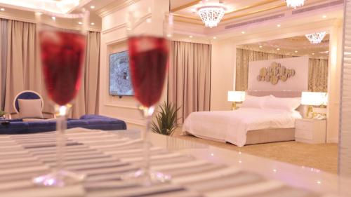 two wine glasses sitting on a table in a bedroom at Broad Almkan Apart Hotel in Taif