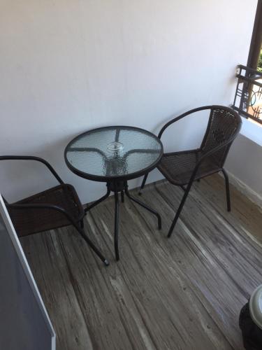a glass table and two chairs in a room at Family Hotel Malibu in Chernomorets