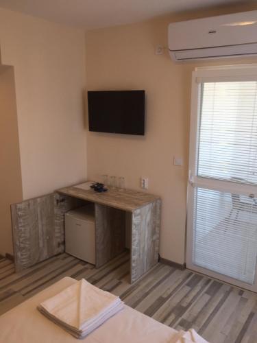 a room with a desk and a television on the wall at Family Hotel Malibu in Chernomorets