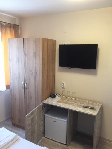 a room with a desk with a television on the wall at Family Hotel Malibu in Chernomorets