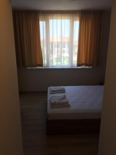a bedroom with a bed and a window with curtains at Family Hotel Malibu in Chernomorets