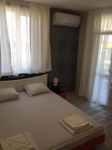 a bedroom with a bed with white sheets and windows at Family Hotel Malibu in Chernomorets