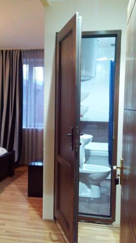 a bathroom with a toilet and a wooden door at Lomari's Guest House in Mestia