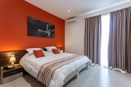 ein Schlafzimmer mit einem Bett mit einer orangefarbenen Wand in der Unterkunft The Shipwright's Lodge in Marsaxlokk