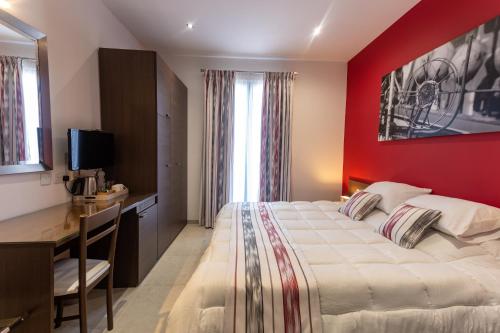 a bedroom with a large bed with a red wall at The Shipwright's Lodge in Marsaxlokk