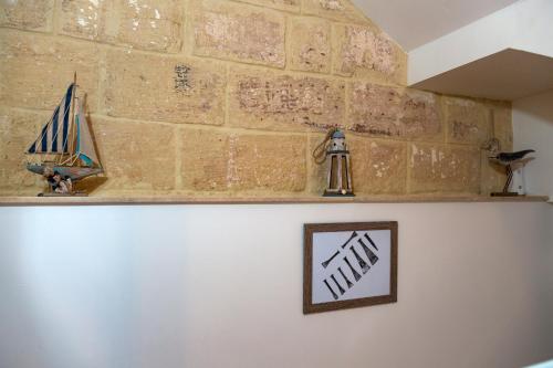 a brick wall with shelves and a picture of a sailboat at The Shipwright's Lodge in Marsaxlokk