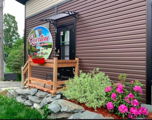 a wooden bench next to a house with flowers at Le Loft Riverstone CITQ 3O1849 in Saint Pierre de Broughton