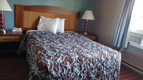 a hotel room with a bed with a comforter at Belmont Inn in Sudbury