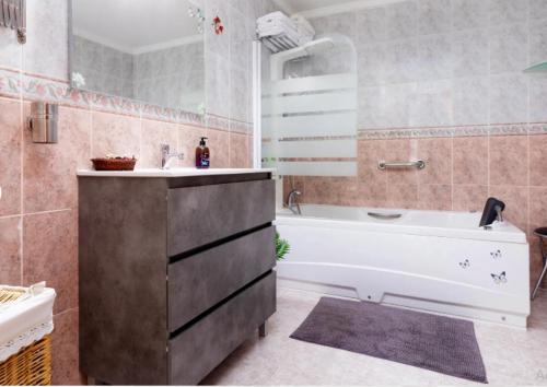 een badkamer met een bad, een wastafel en een bad bij Casa Sandra in Corralejo