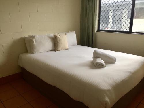 Una cama blanca con una toalla encima. en Koala Beach Resort Cairns, en Cairns