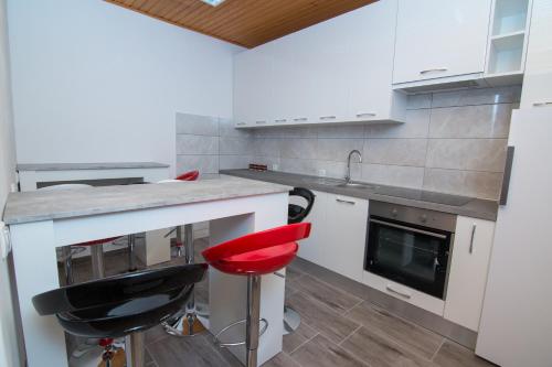 a kitchen with a counter and two red stools at Hostel Flora in Mali Lošinj
