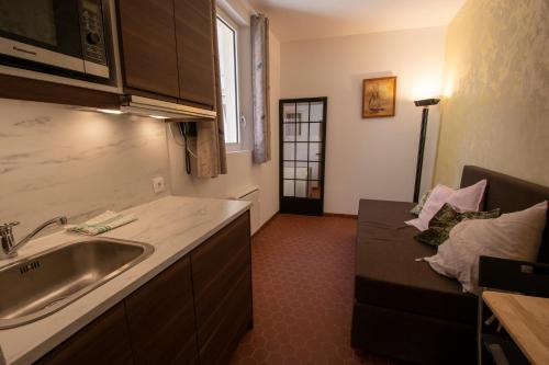 a kitchen with a sink and a couch in a room at A l'ombre du Palais in Avignon