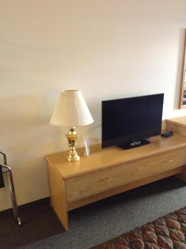 a television on a wooden table with a lamp at Coeur D' Alene Budget Saver Motel in Coeur d'Alene