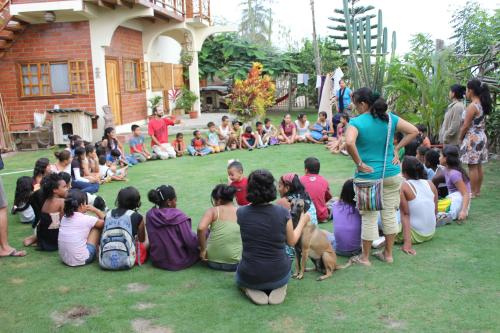 a group of people sitting on the grass watching a man with a dog at The Sea Garden House in Olón