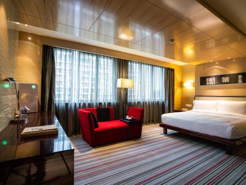 um quarto de hotel com uma cama e uma cadeira vermelha em Fortune Hotel Fuzhou em Fuzhou