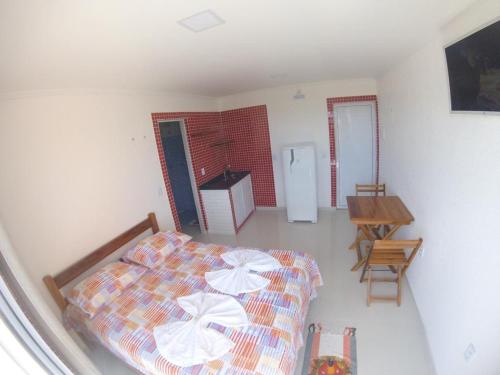 a bedroom with a bed and a table and a refrigerator at Flat com Varanda e Vista Mar in Paracuru