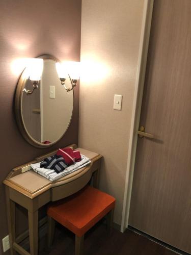 a bathroom with a vanity with a mirror and a stool at Hotel Patio Dogo in Matsuyama