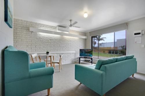 a living room with two blue chairs and a table at Hybiscus Waterfront Apartments in Lakes Entrance