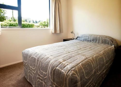 een slaapkamer met een groot bed en een raam bij Dragonfly Cottage in Wanaka