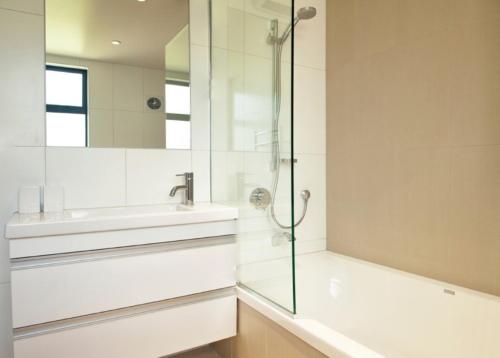 a bathroom with a glass shower and a sink at Dragonfly Cottage in Wanaka