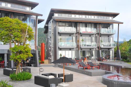 a building with a pool and tables and an umbrella at The Houben - Adult Only in Ko Lanta
