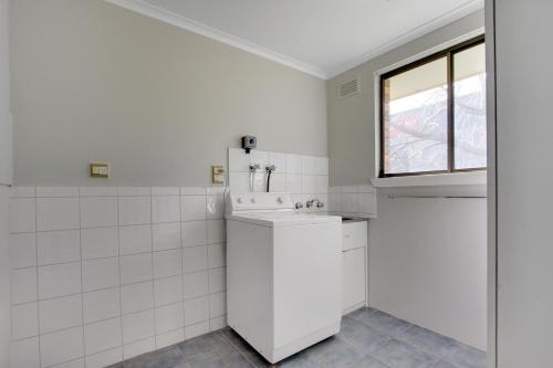 a white bathroom with a sink and a window at Hybiscus Waterfront Apartments in Lakes Entrance