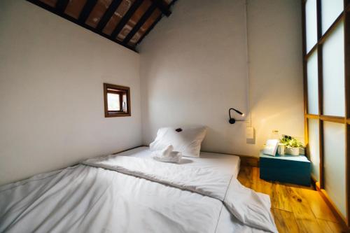 a bedroom with a bed with white sheets and a window at a-mâze house in Hue