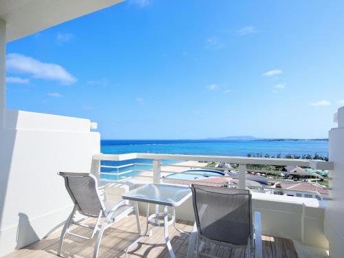 a balcony with chairs and a table and the ocean at Sheraton Okinawa Sunmarina Resort in Onna