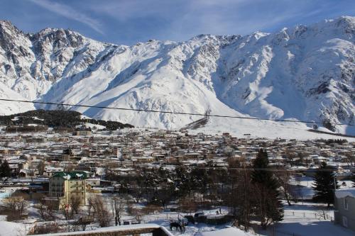 una città nella neve con montagne sullo sfondo di Ketino's Home a Kazbegi
