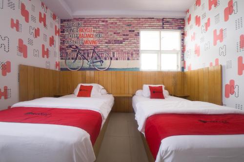 two beds in a room with a bike on the wall at RedDoorz Plus Syariah @ Pentadio Gorontalo in Gorontalo