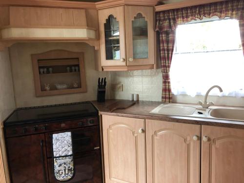 a kitchen with wooden cabinets and a sink at Lyndhurst 39 in Dunoon