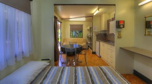 a bedroom with a bed and a table and a kitchen at Kookaburra Holiday Park in Cardwell