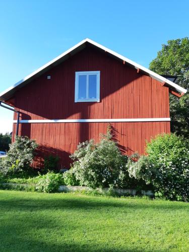 um celeiro vermelho com uma janela do lado dele em Sörtorpets gårdshus em Älvkarleby