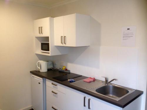 
a kitchen with a white counter top and white cabinets at Abel Tasman Airport Motor Inn in Launceston
