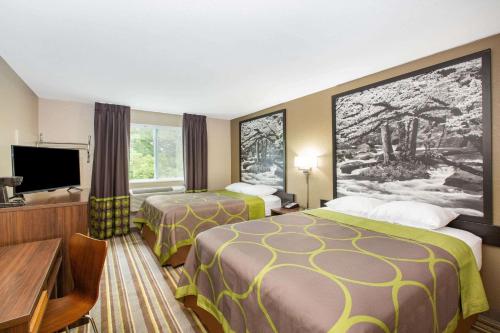 a hotel room with two beds and a flat screen tv at Super 8 by Wyndham Chattanooga Lookout Mountain TN in Chattanooga