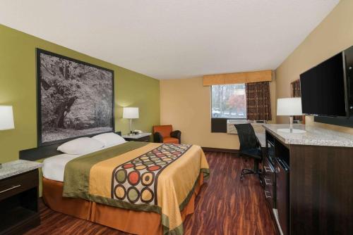 a hotel room with a bed and a television at Super 8 by Wyndham Raleigh North East in Raleigh