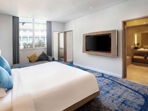 a hotel room with a bed and a flat screen tv at Novotel Jakarta Mangga Dua Square in Jakarta