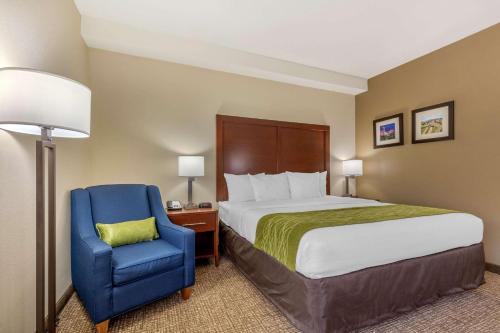 a hotel room with a bed and a blue chair at Comfort Inn Lenoir City-Knoxville in Lenoir City