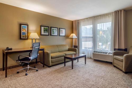a hotel room with a couch and a desk and a chair at Comfort Inn & Suites Perry National Fairgrounds Area in Perry