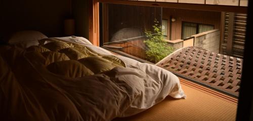 uma cama não feita sentada no peitoril da janela com uma saia-cama em Yado Kiramachi em Quioto