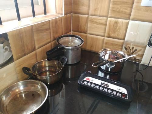 a kitchen counter with pots and pans on a stove at Lakshmi Nilaya Family Homestay on Hilltop-360 Degree View in Madikeri
