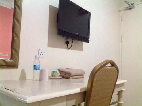 a desk with a television on a wall with a chair at Hotel Morning Glory in Kudat
