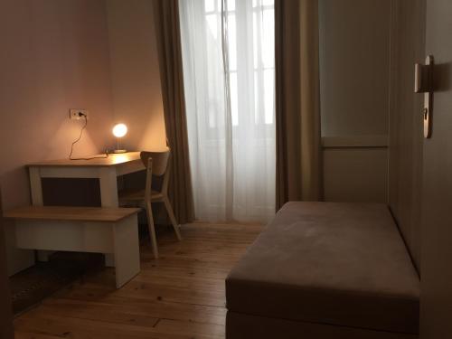 Cette petite chambre comprend un bureau, un lit et une lampe. dans l'établissement Villa Tarbis Tarbes centre ville , appartements tout confort, à Tarbes