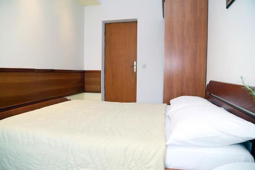 1 dormitorio con cama blanca y puerta de madera en Apartments Ardura, en Petrovac na Moru