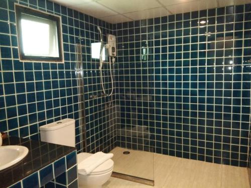 a blue tiled bathroom with a toilet and a shower at Scent of Sukhothai Resort in Sukhothai