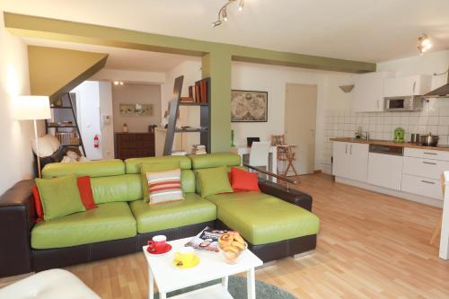 uma sala de estar com um sofá verde e uma mesa em COLMARAPPART Grand'Rue em Colmar