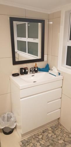 uma casa de banho com um lavatório branco e um espelho. em Te Etu Villa 2 em Rarotonga