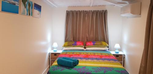 a bedroom with a bed with a colorful blanket at Te Etu Villa 2 in Rarotonga